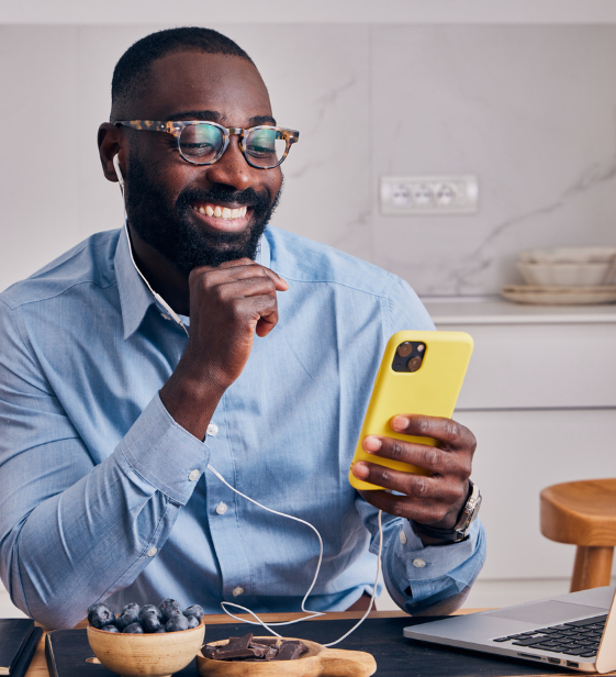 A remote employee smiles during a virtual coaching session, accessing personalized support through the Exos app from his kitchen table.