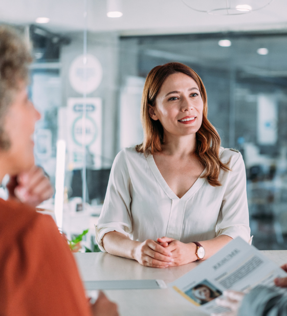 Woman in a job interview smiling confidently, as two professionals review her résumé — highlighting the importance of supporting women’s health in the workplace.