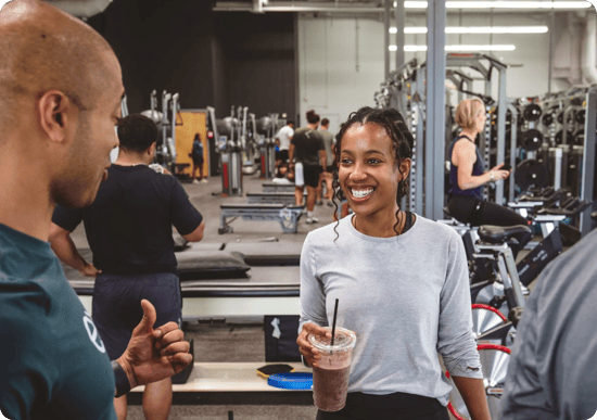 Smiling employee in an Exos fitness center, reflecting Pfizer’s unified wellness experiences.